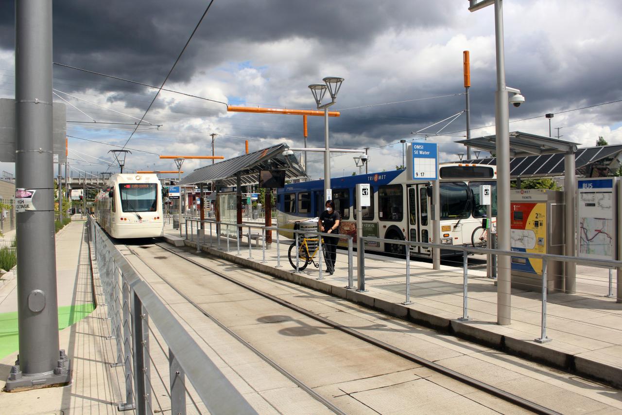 A masked passenger with a bicycle standing at a multimodal station.